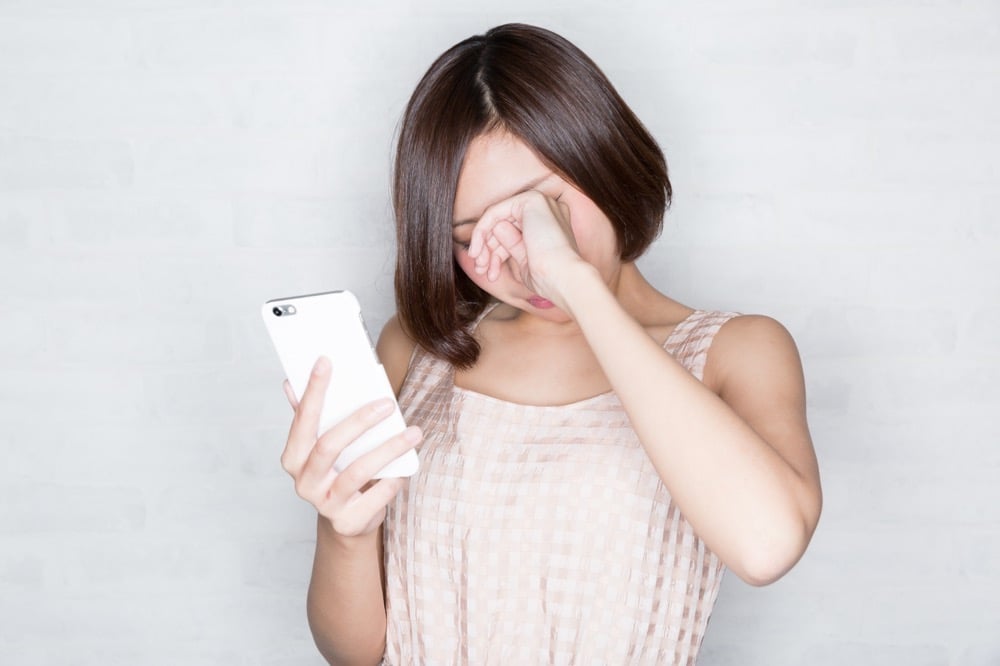 イメージ：スマホを見て、目が疲れている女性