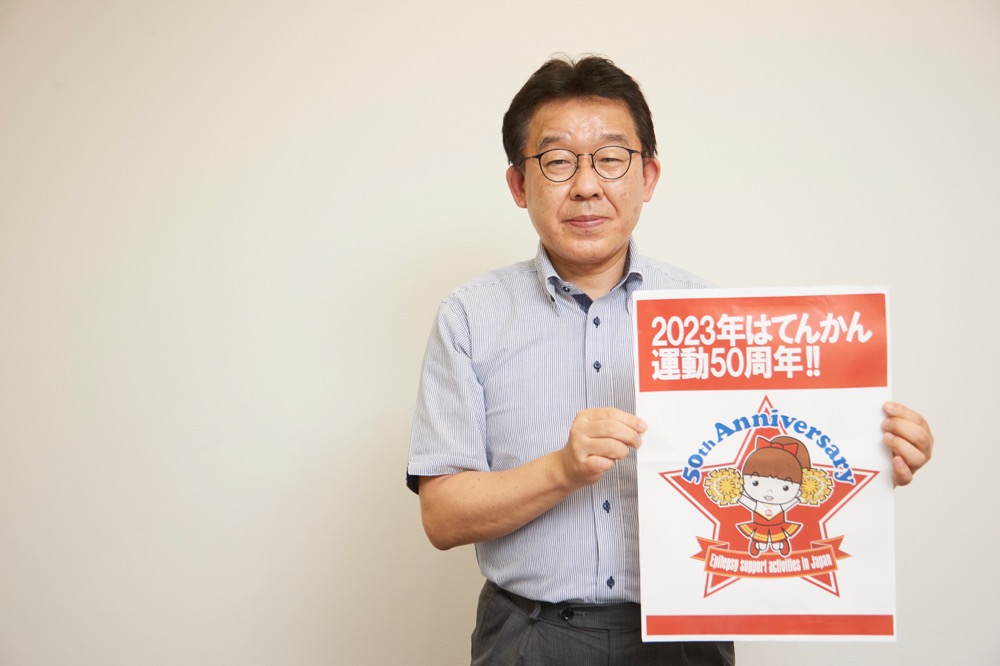 てんかん運動50周年のポスターを手に持つ田所さん