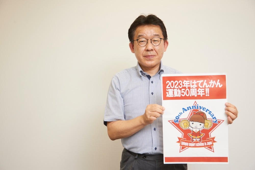 てんかん運動50周年のポスターを手に持つ田所さん