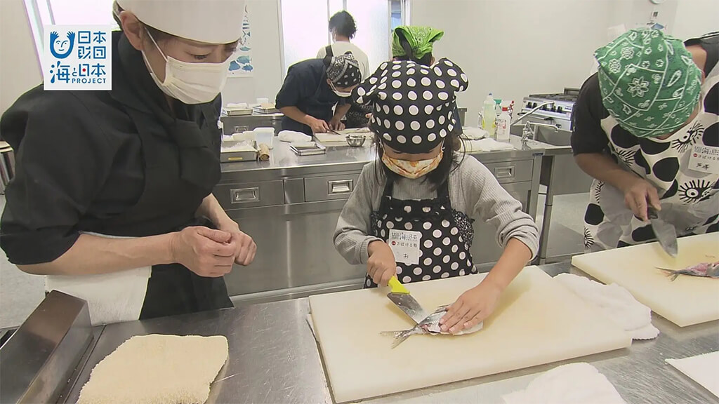 A child learning the san-mai oroshi technique to fillet aji