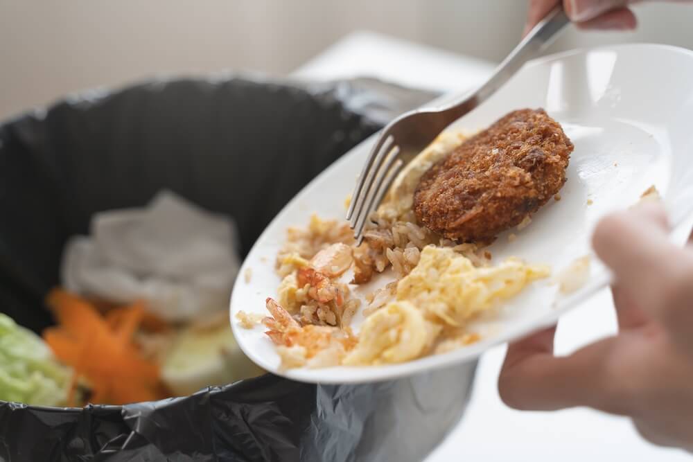 イメージ：食べ残しをゴミ箱に捨てる様子