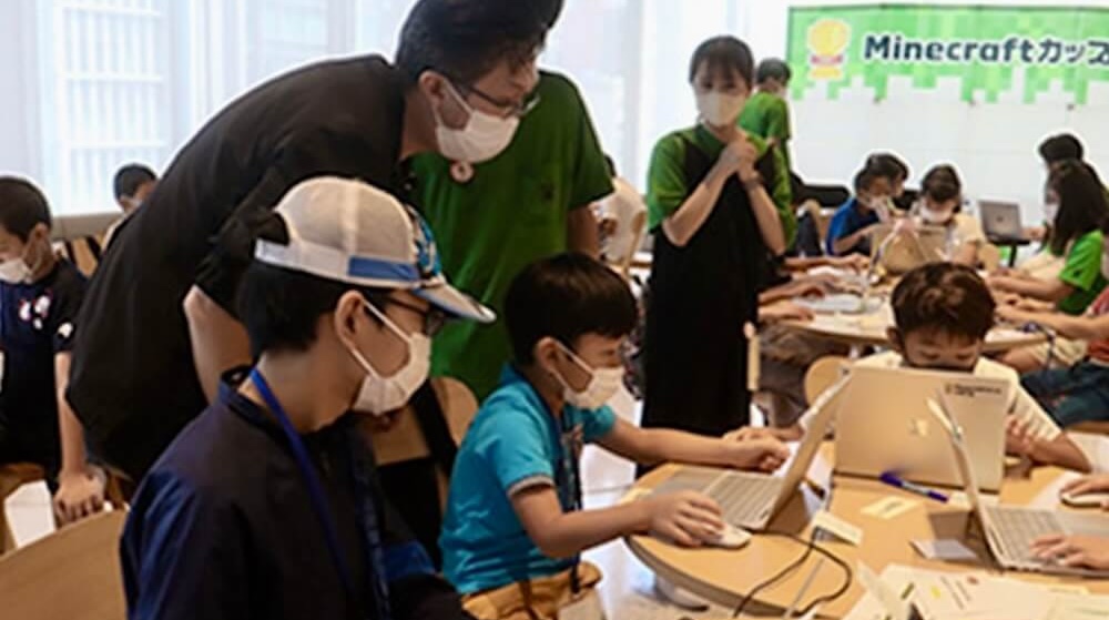 Photo of Shyuichi Tatsunami giving advice to students at a Minecraft workshop