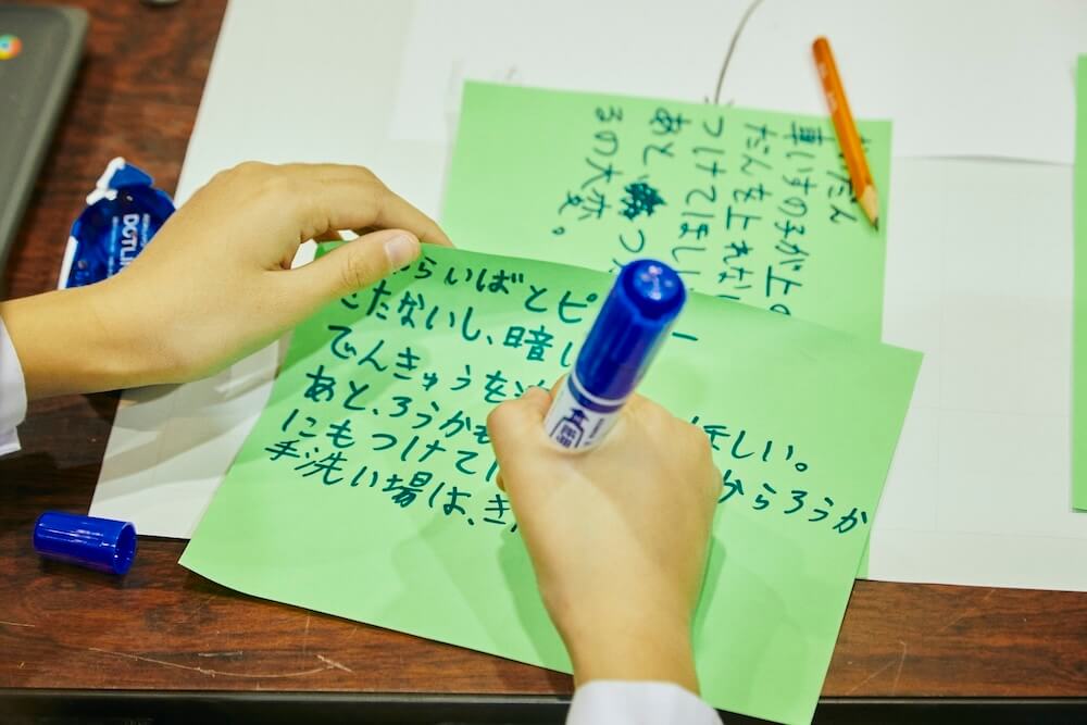 写真：バリアフリー化のアイデアを大きな付箋に書く児童