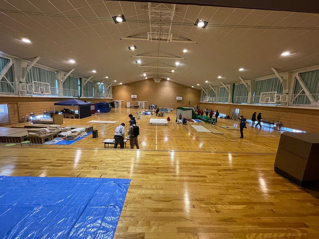 Photo of a gymnasium where cardboard beds are about to be installed
