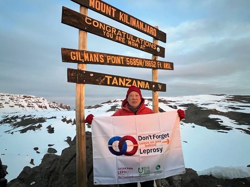 Photo of Yohei Sasakawa holding a “Don’t Forget Leprosy” banner on Mt. Kilimanjaro