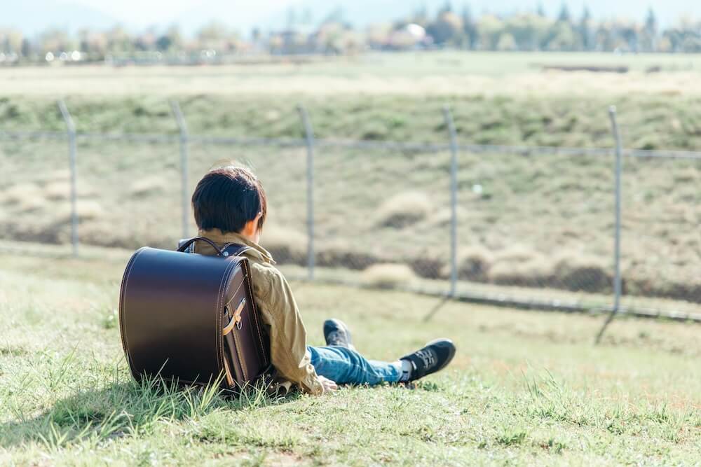 イメージ写真：河原にひとりぼっちで座り込む子ども