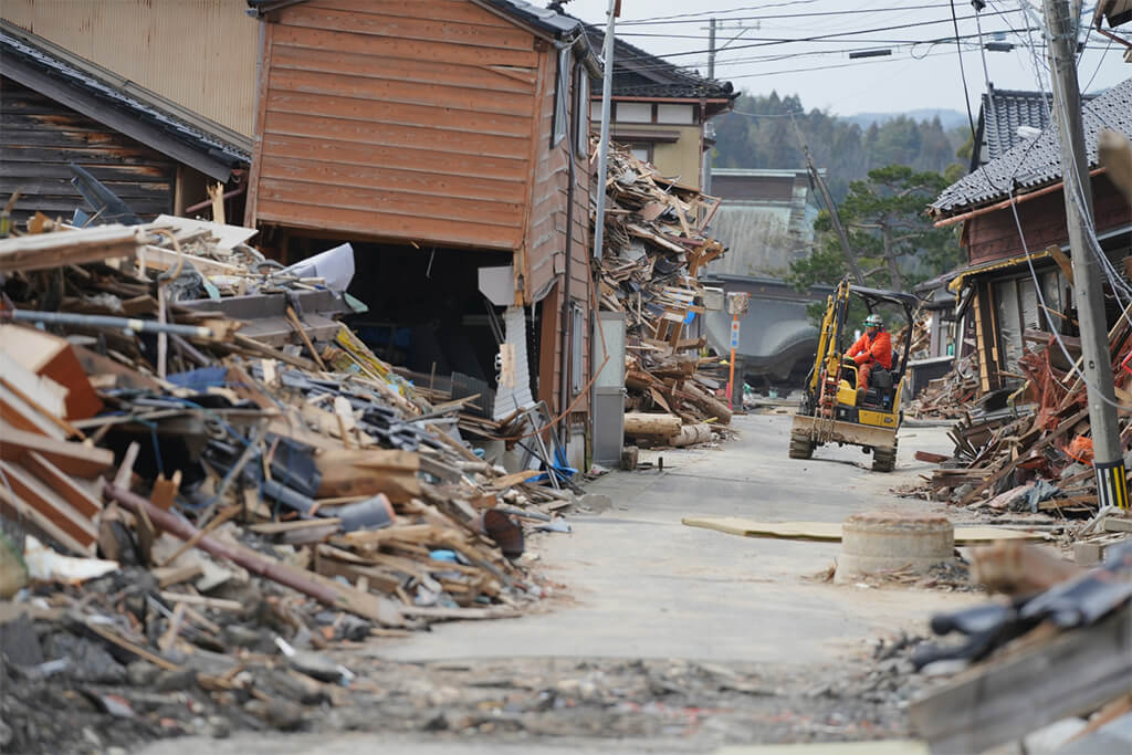 写真：珠洲市の様子。家屋が倒壊し、車一台通るのがやっとの道幅となっている。