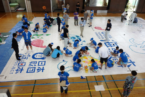 Photo of children and adult volunteers painting the Kugi-no-Nai beach house covering (1)