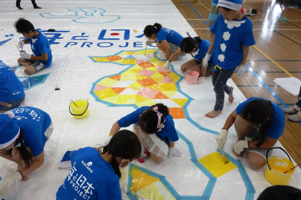 Photo of children and adult volunteers painting the Kugi-no-Nai beach house covering (2)
