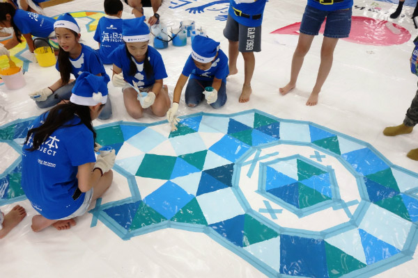 Photo of children and adult volunteers painting the Kugi-no-Nai beach house covering (3)