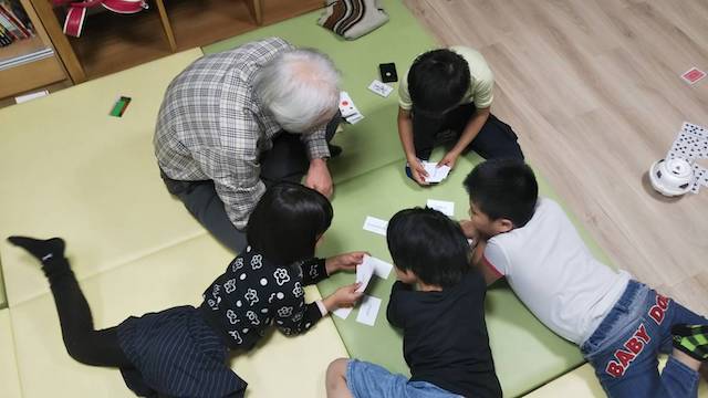写真:カルタで遊ぶ子供たちとボランティア