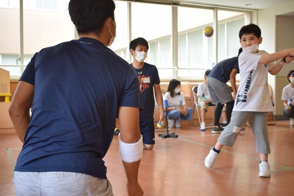 写真:院内でアスリートと野球をする子供たち