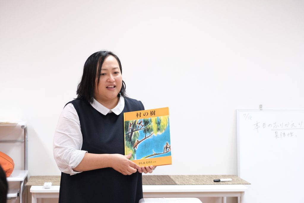 写真:絵本「村の樹」を紹介する酒井さん