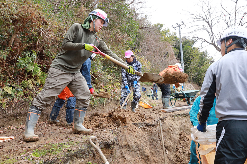 写真:崩れた道を補修するボランティア。複数の作業員が、スコップで土砂をかき出している(一般社団法人OPEN JAPAN提供 )