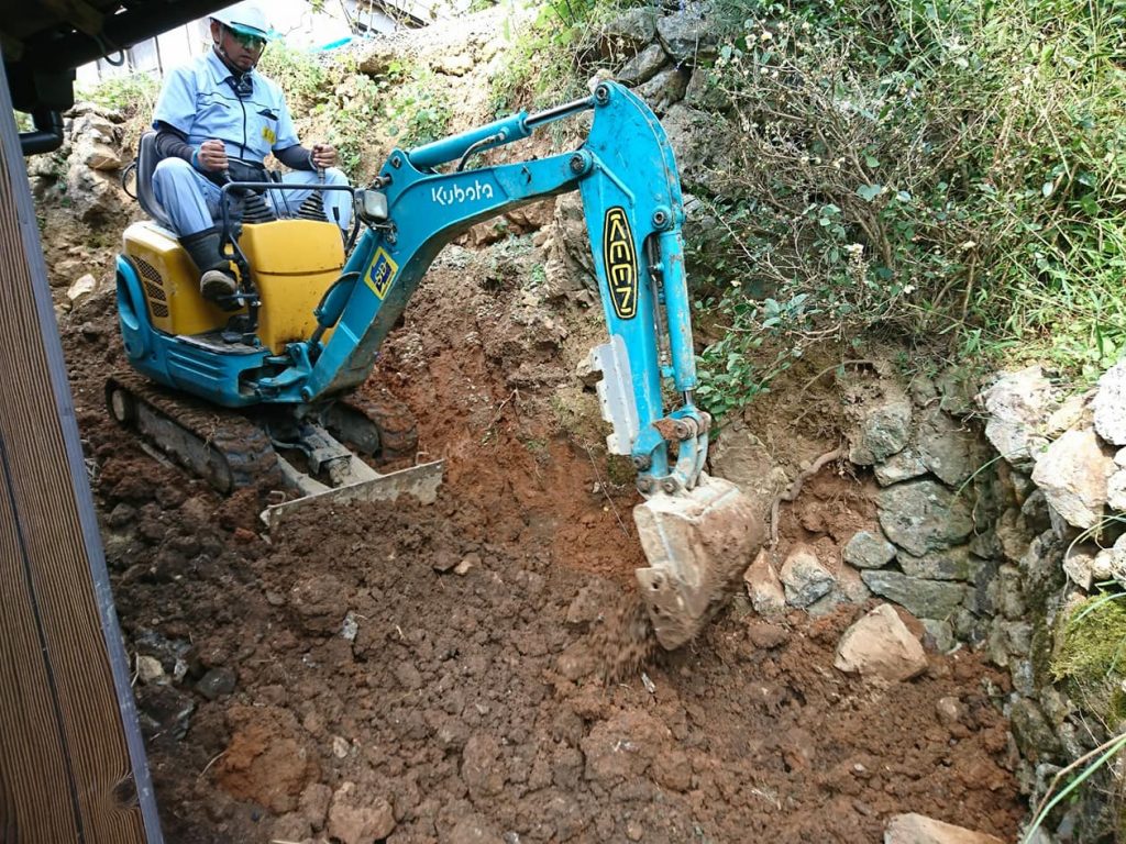 写真:西日本豪雨の被災地・愛媛県西予市で、土砂でできた斜面の上で重機を操作する萬代さん(2018年10月、萬代さん提供)