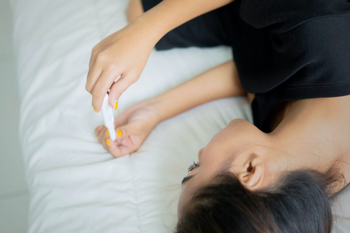 写真：陽性の反応を示す妊娠検査薬を眺める女性
