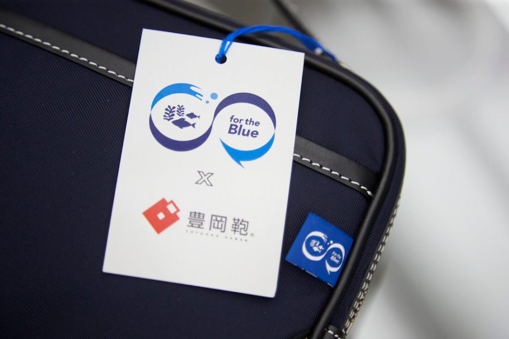 写真:廃棄漁網由来のかばんに付けられた「Product for the Blue」のロゴデザインが入ったタグ