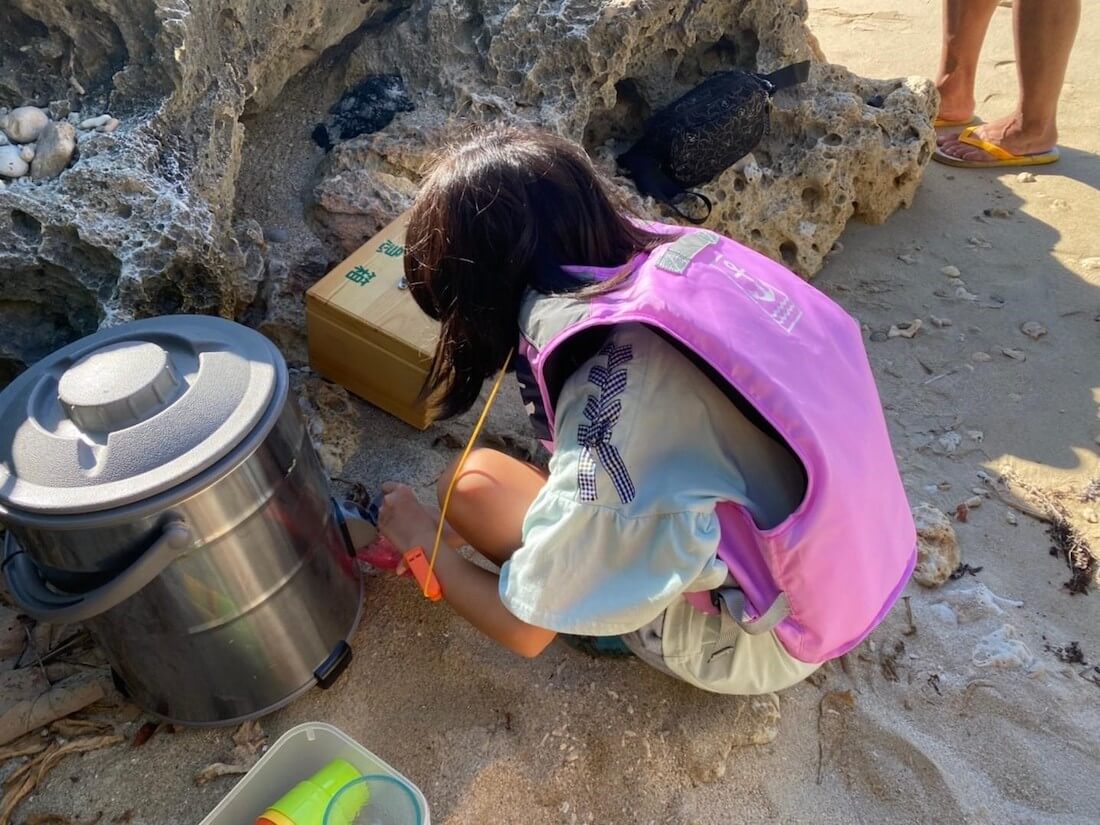 写真:海岸で遊ぶライフジャケットを着用した子ども