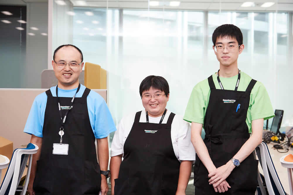 写真:左からブルー、ホワイト、グリーンのユニフォームを着た3人の社員さん