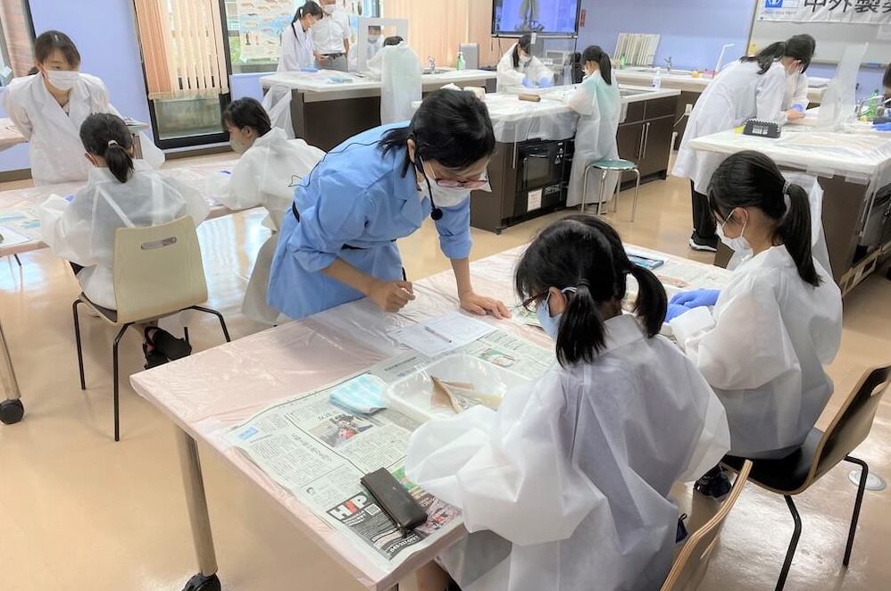写真:実験室で講師に教えてもらいながら実験に取り組む子どもたち