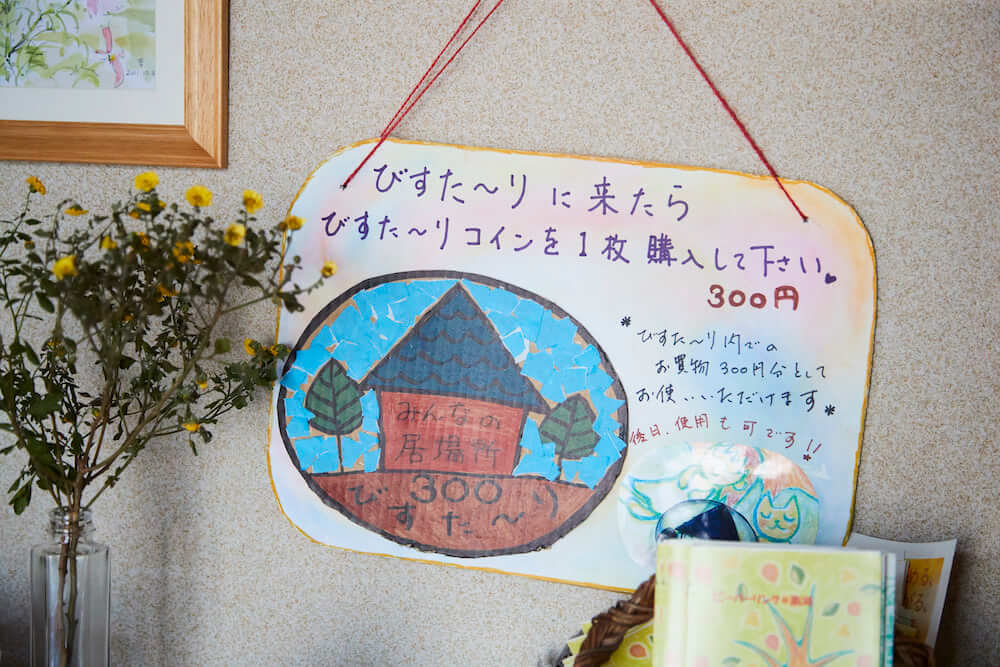 写真:玄関に飾られた「びすた~りコイン」の説明が書かれたボード