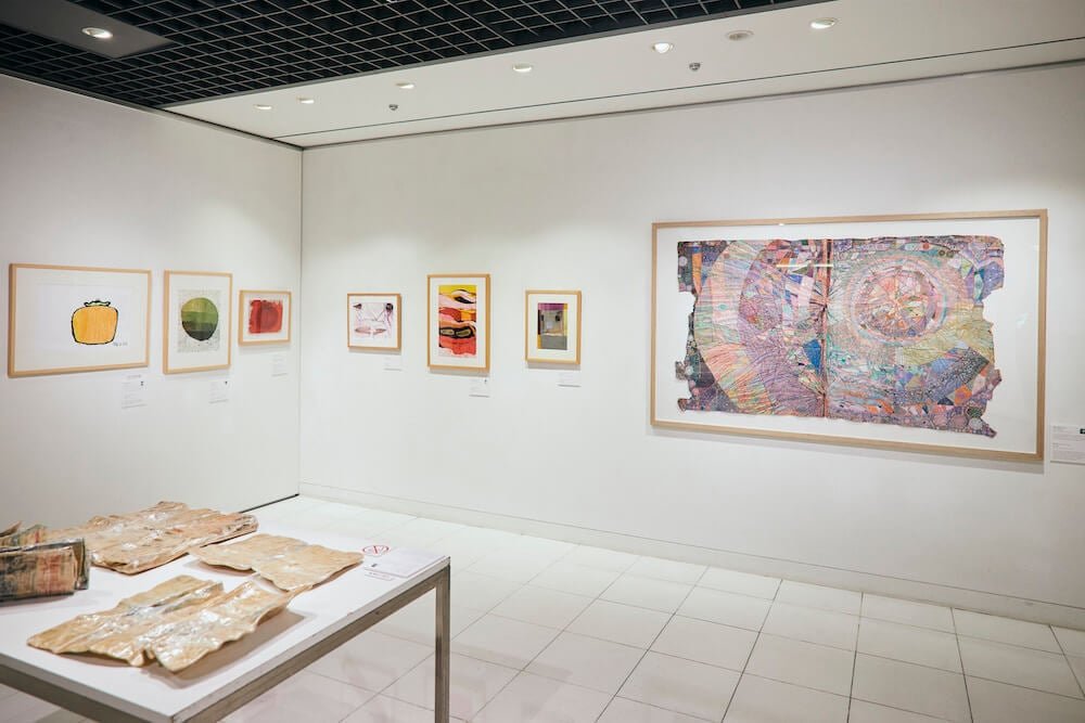 写真:壁に絵画、机の上に立体作品が並んでいる