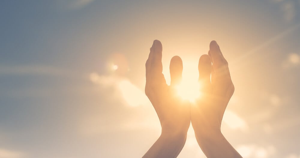 写真:太陽に向かって、かざす手(イメージ)