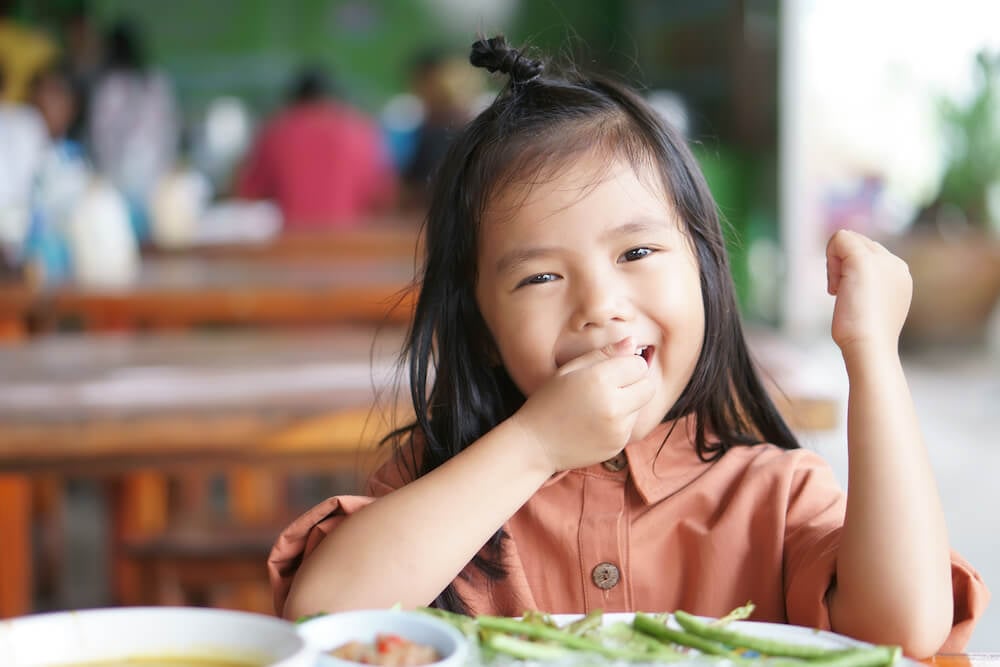 こども食堂でご飯を食べる笑顔の少女(イメージ)