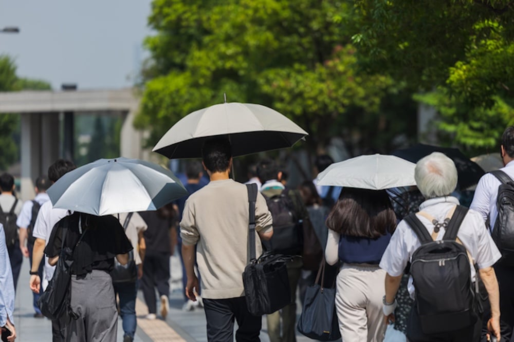 日傘を差し街を歩く大勢の人々
