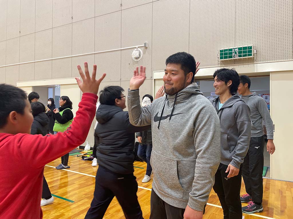 写真:子どもたちとハイタッチするHEROsアスリート
