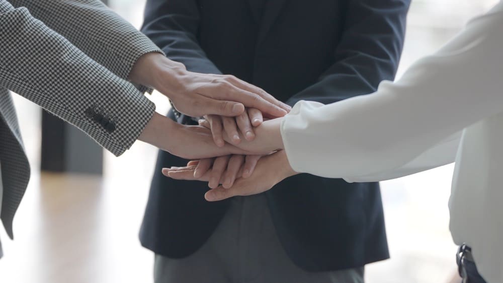 イメージ：エンジンを組み手を重ね合う人たち
