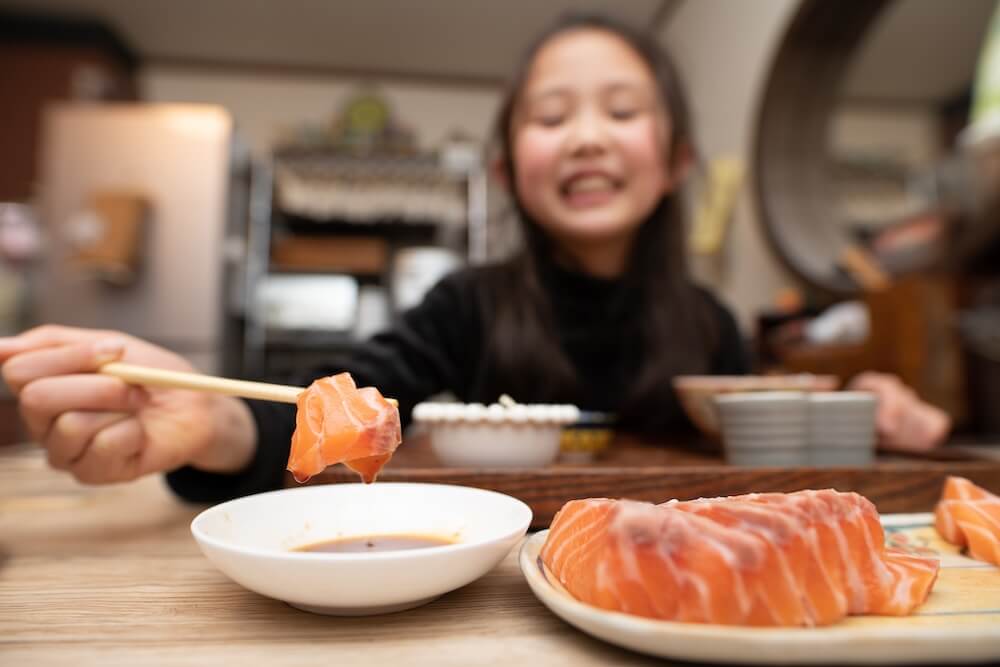 サーモンの刺身を食べる子ども
