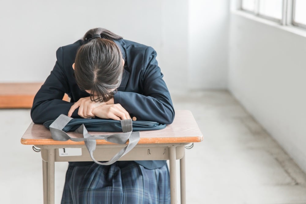 机に伏せる女子学生