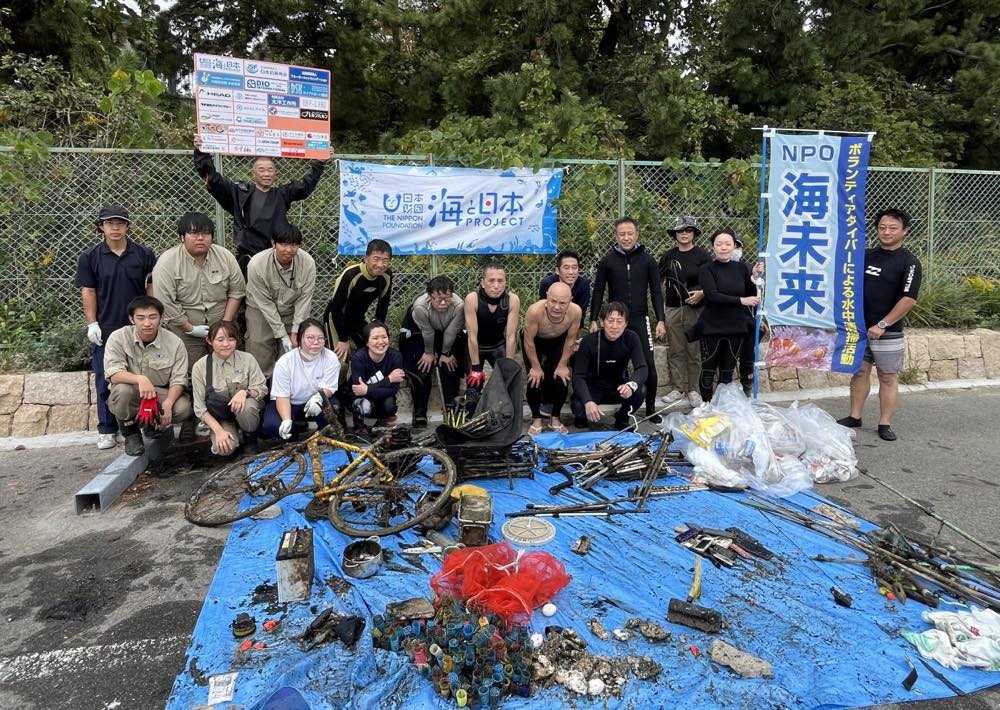 ボランティアダイバーなどが、回収したごみの後ろに並んでいる様子