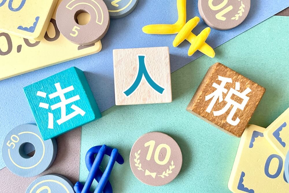 イメージ：法人税という文字の周まわりにお金のおもちゃが散らばっている