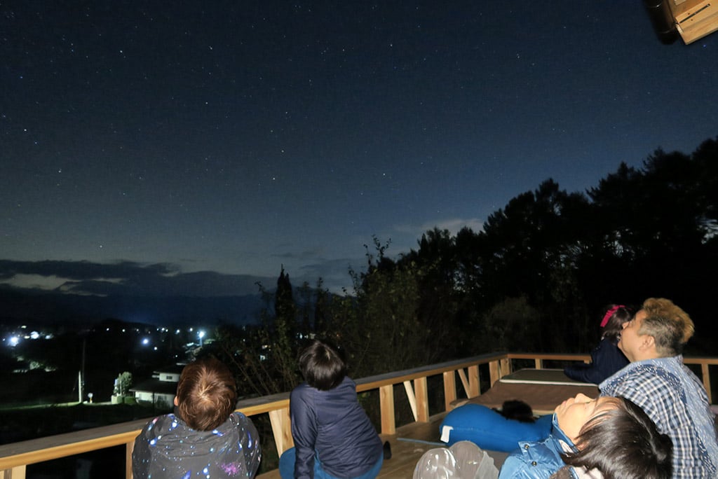 写真：夜の星つむぎの村で星空を見上げる家族の様子。