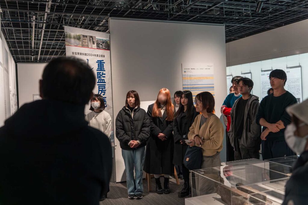 写真：重監房資料館での説明に聞き入る奨学生の様子。