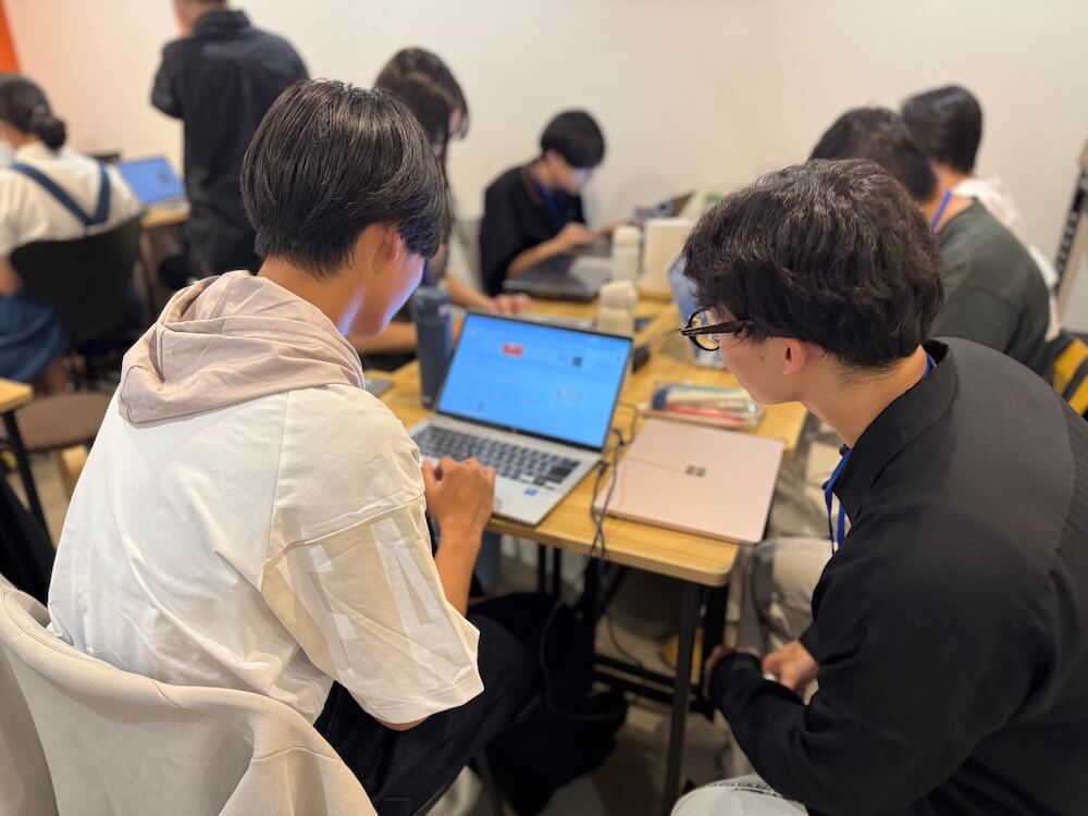 大学生のメンターが、高校生に対しデジタルスキルの習得をサポートしている様子