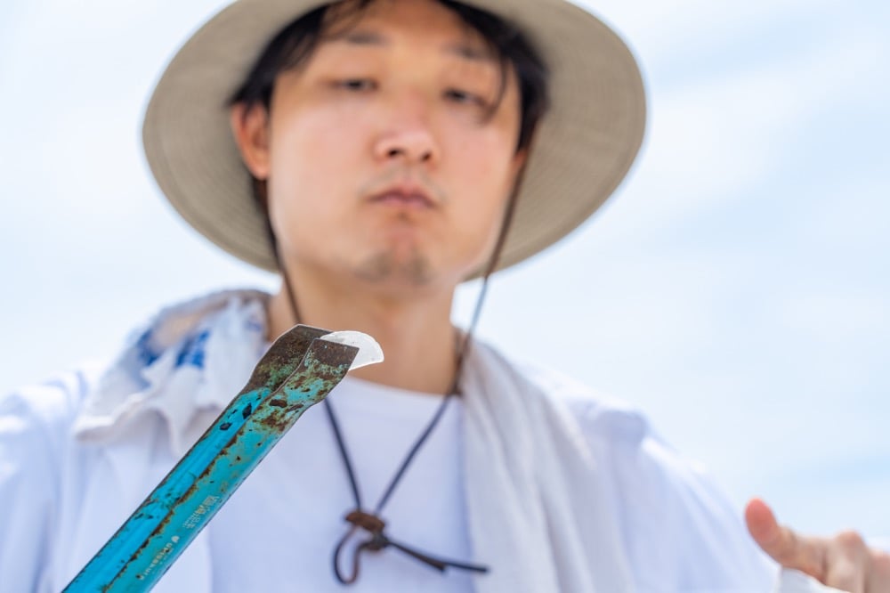 トングでつまんだガラスの破片