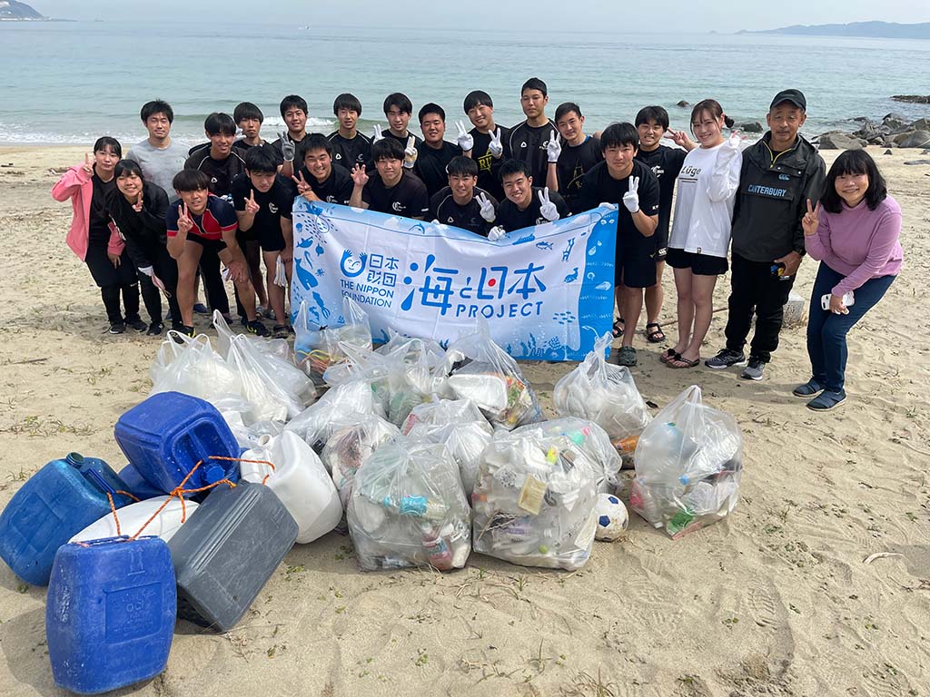 写真：海ごみ拾いイベントで回収された沢山のごみと、イベント参加者たちの集合写真。