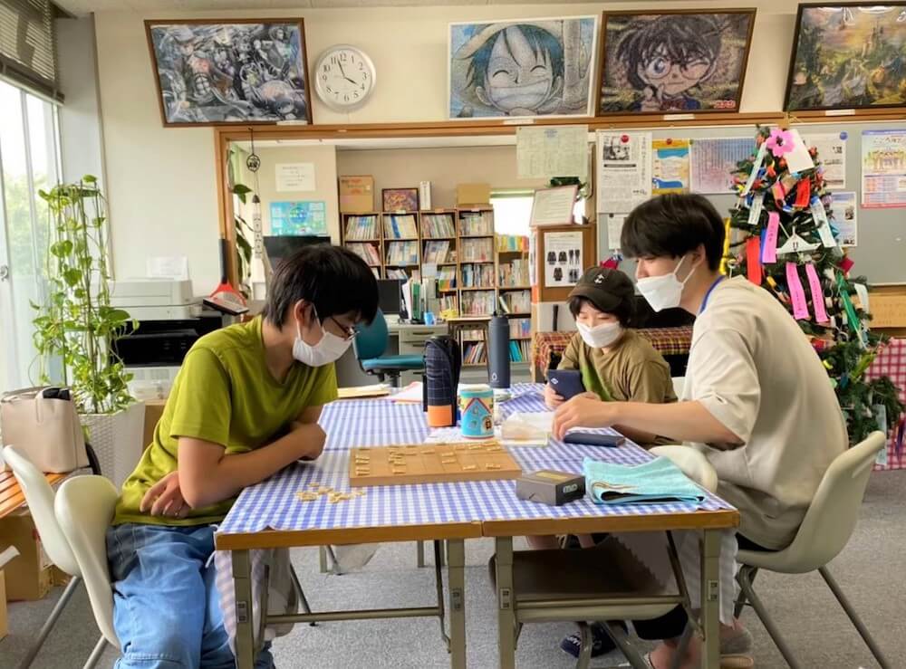 写真：
熊本の子ども第三の居場所で、学生スタッフと将棋を楽しむ子ども