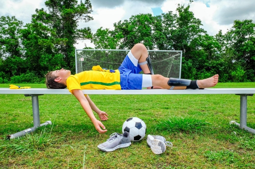 ベンチで倒れるサッカー少年